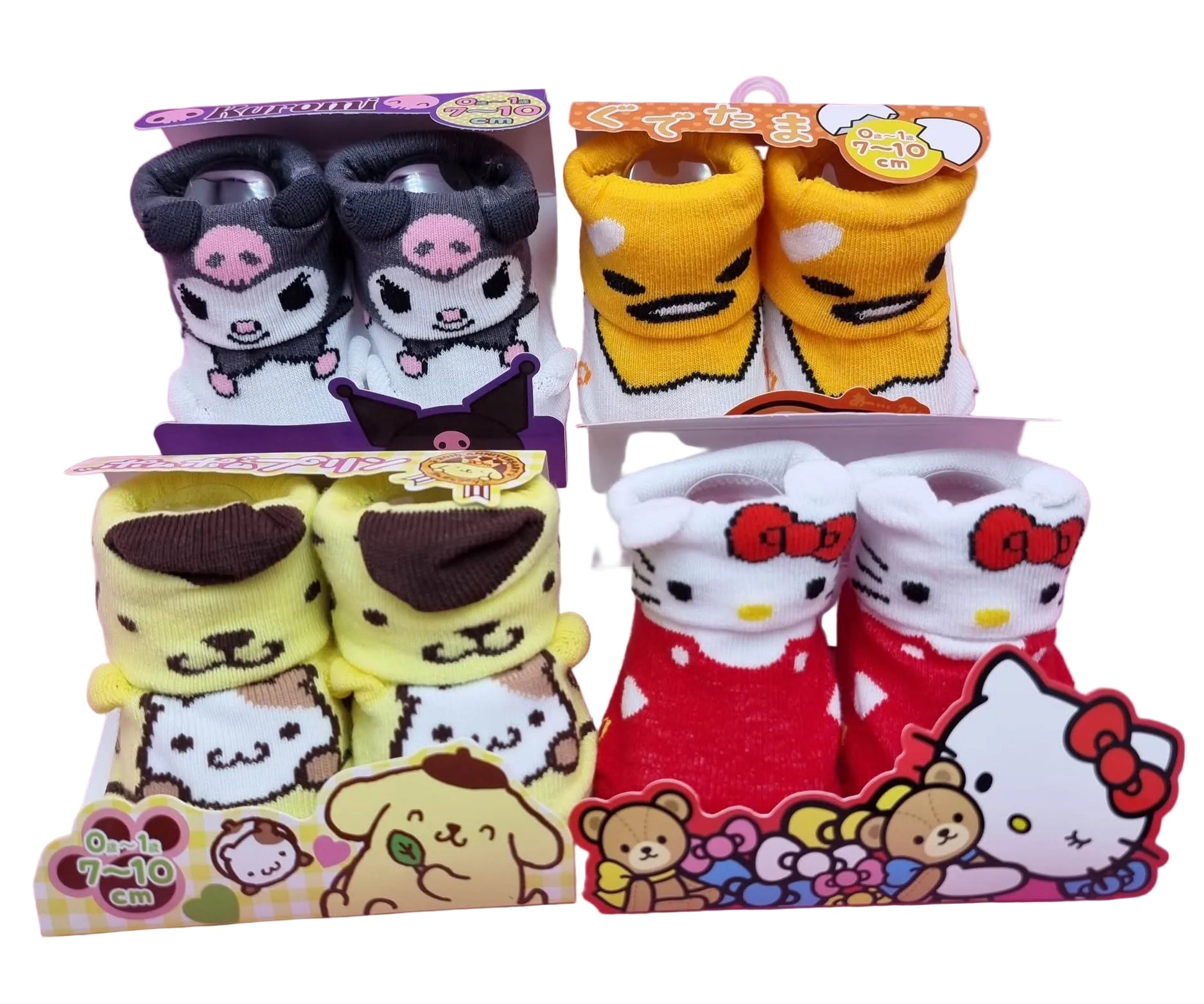 Four pairs of Sanrio baby booties displayed in their original retail packaging on a solid pink background. The set includes Kuromi, Groucho, Pompompurin, and Hello Kitty booties.